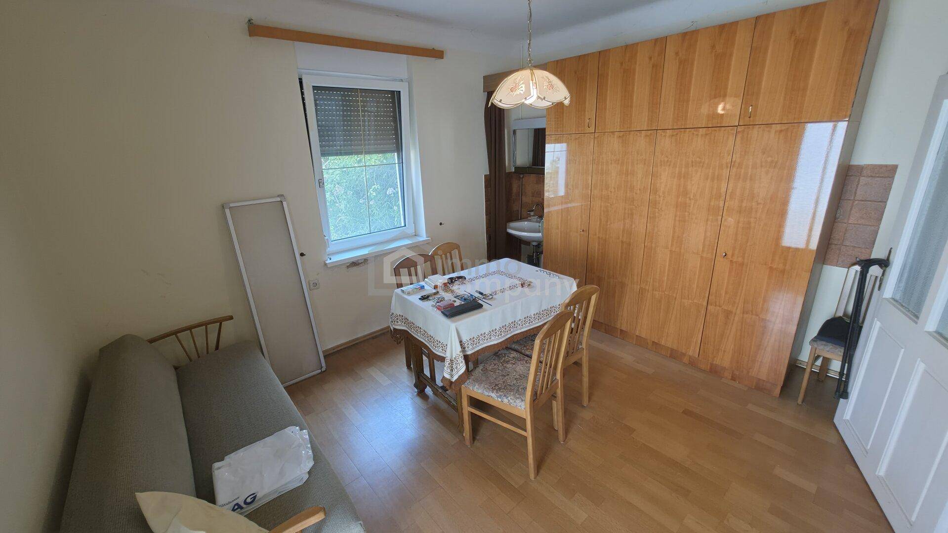 Essbereich mit Holztisch, Stühlen, einem Sofa und einem großen Holzschrank.