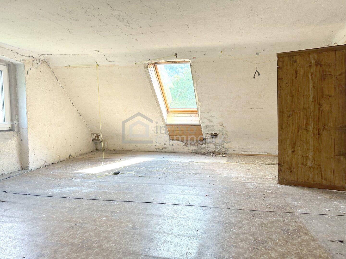 Dachzimmer mit Dachschräge, Dachfenster und sichtbaren Gebrauchsspuren.