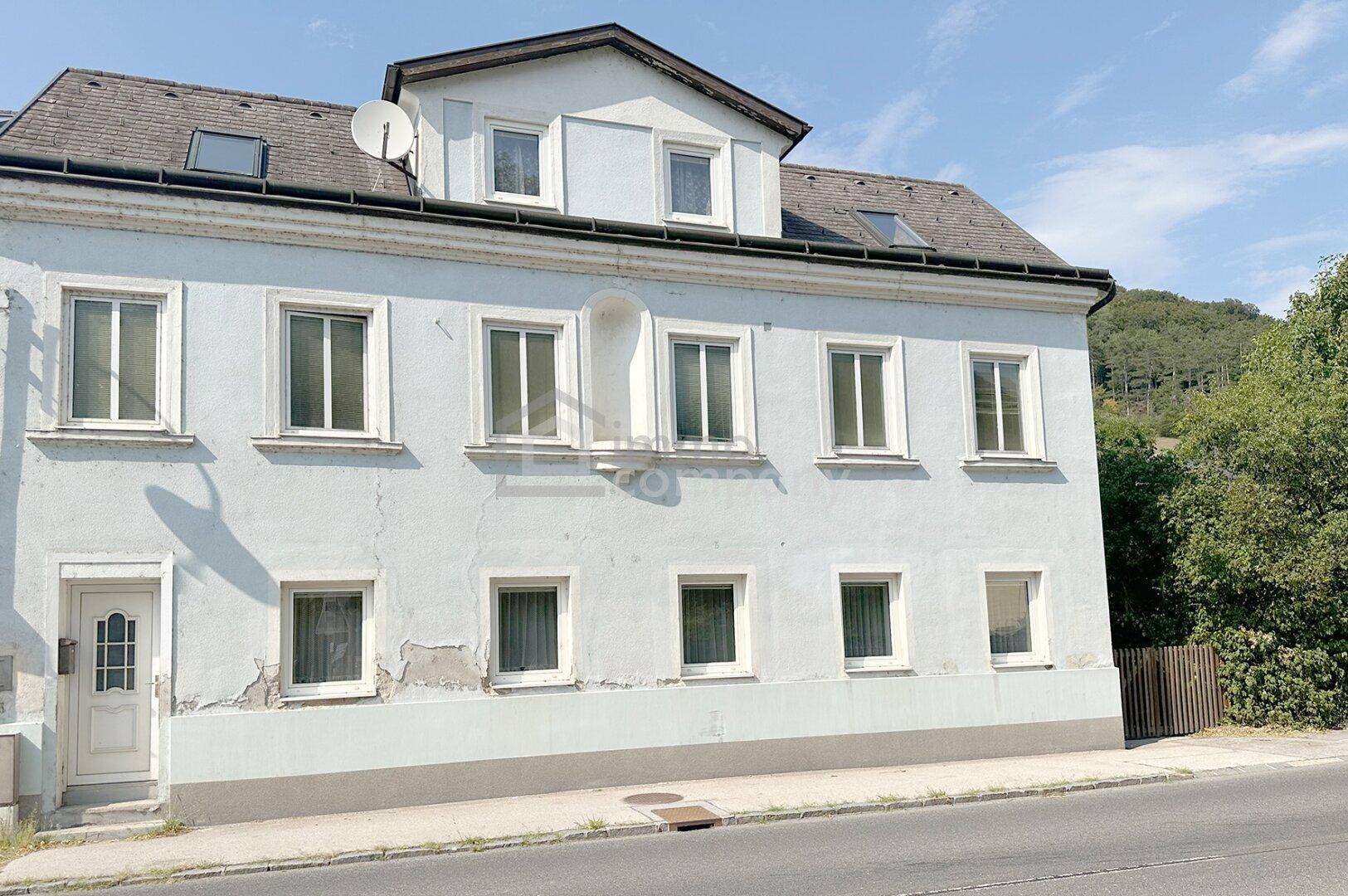 Vorderansicht des alten Gebäudes mit mehreren Fenstern und einem Eingangsbereich.
