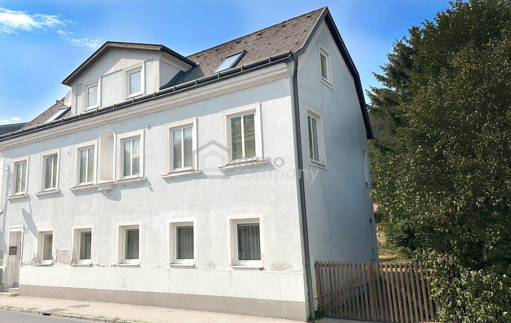 Seitenansicht eines älteren Gebäudes mit Dachfenstern und einfacher Fassade.