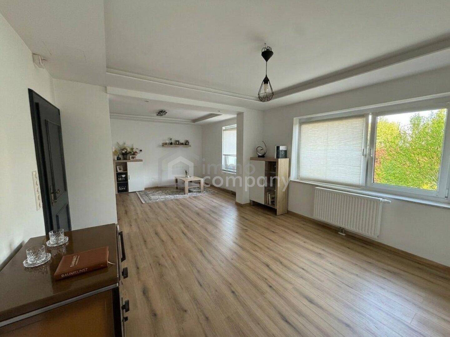 Helles Wohnzimmer mit modernem Laminatboden und großen Fenstern für viel Tageslicht.