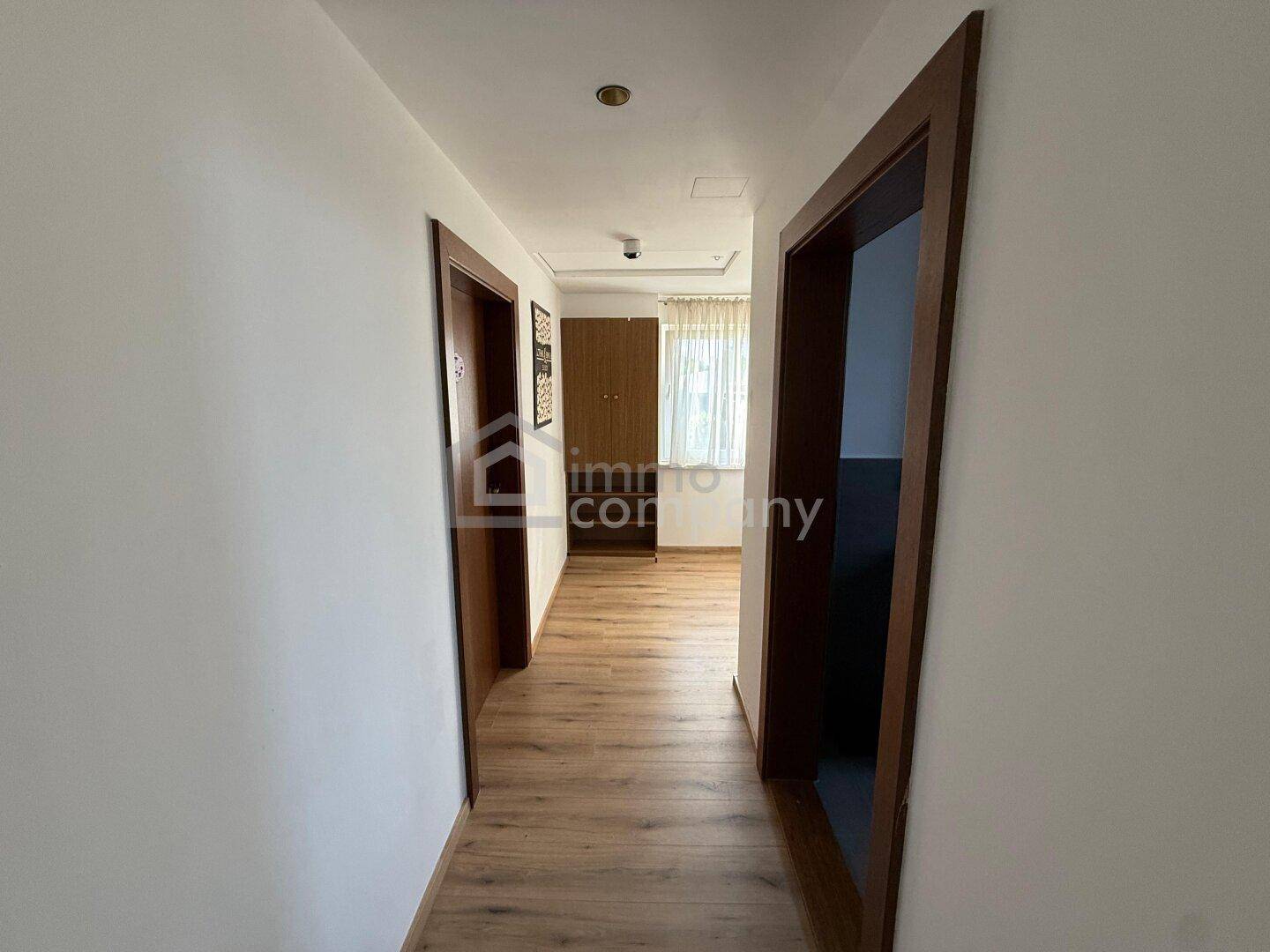 Heller Flur mit Laminatboden und Holztüren, der zu den verschiedenen Räumen führt.