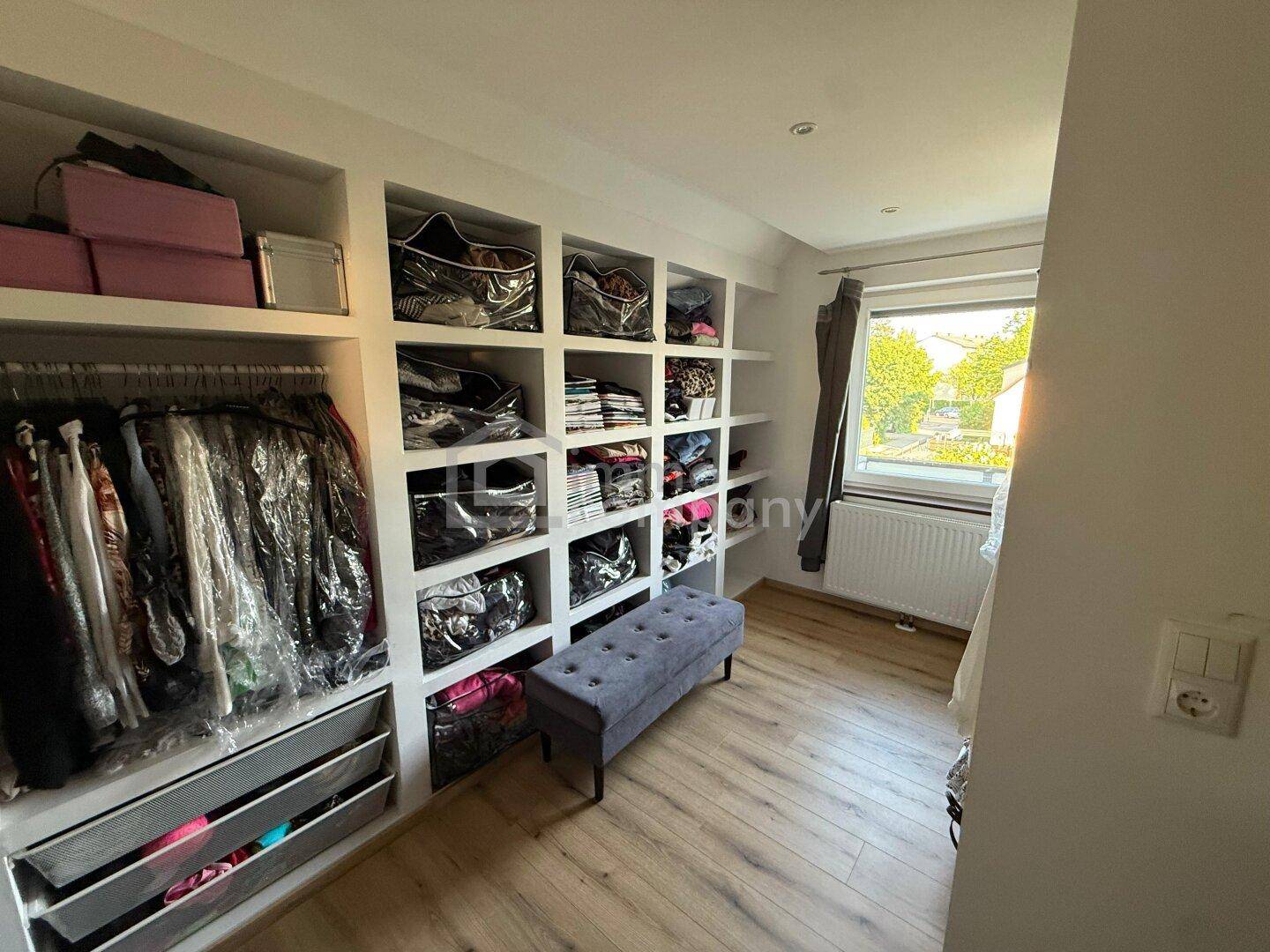 Praktischer begehbarer Kleiderschrank mit vielen Regalen und Stauraum für Kleidung.
