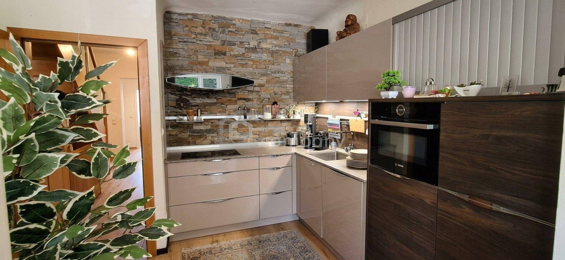 Moderne Küche mit Steinwand, integrierten Geräten und viel Stauraum in eleganten Schränken.