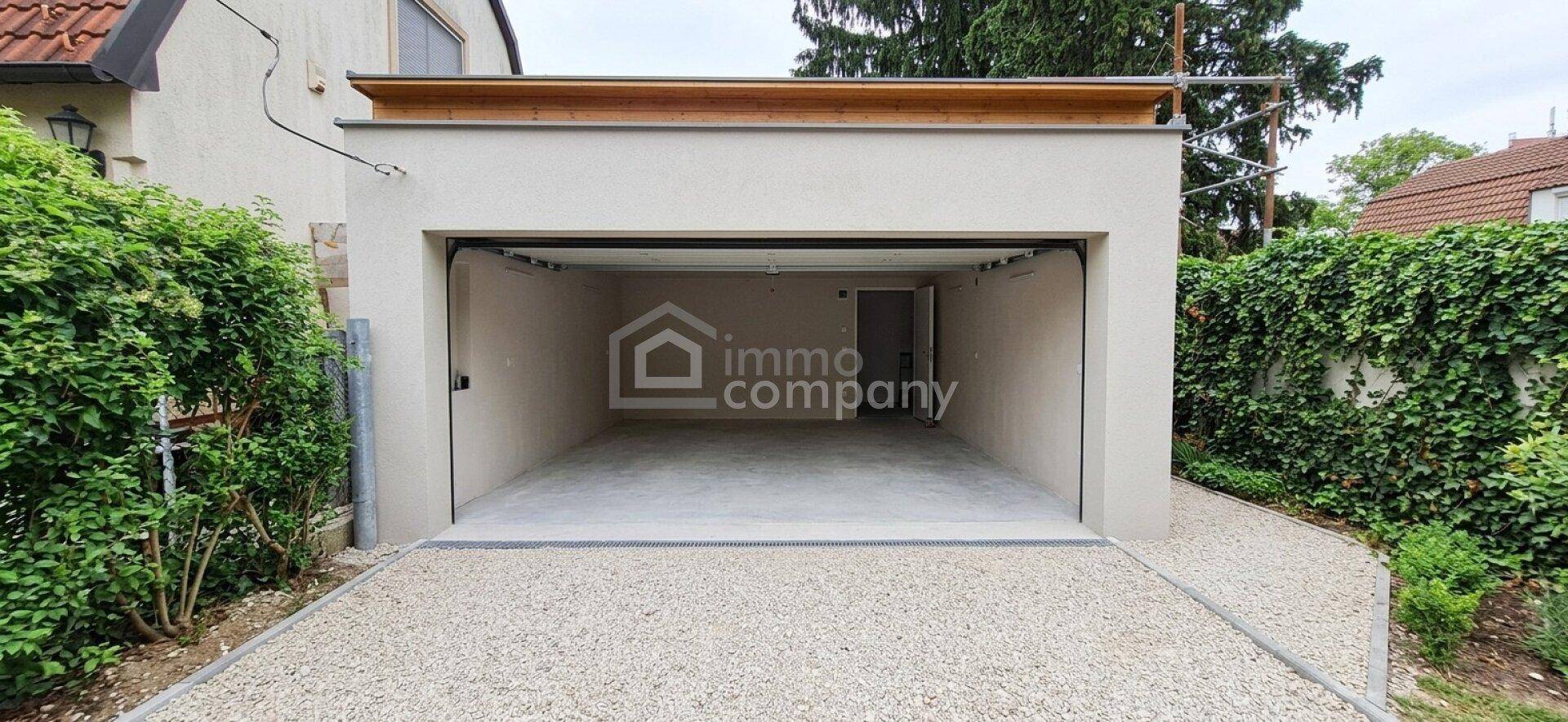 Geräumige, offene Garage mit Betonboden und direktem Zugang zur Kiesauffahrt.