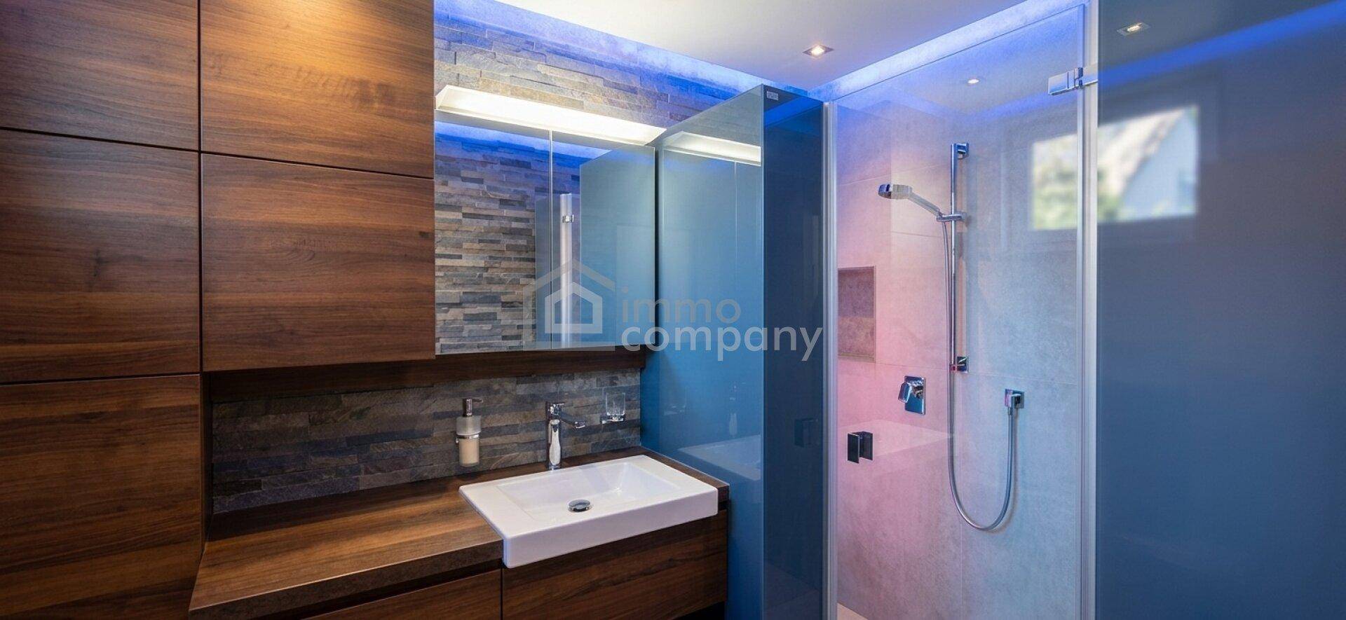 Modernes Badezimmer mit begehbarer Dusche, Holzwaschtisch und stimmungsvoller Beleuchtung.