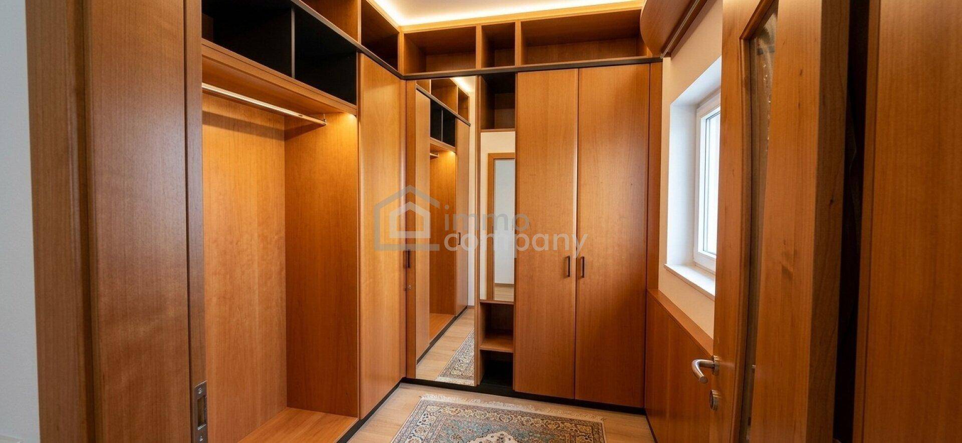 Geräumiger begehbarer Kleiderschrank mit viel Stauraum und integrierten Spiegeln.