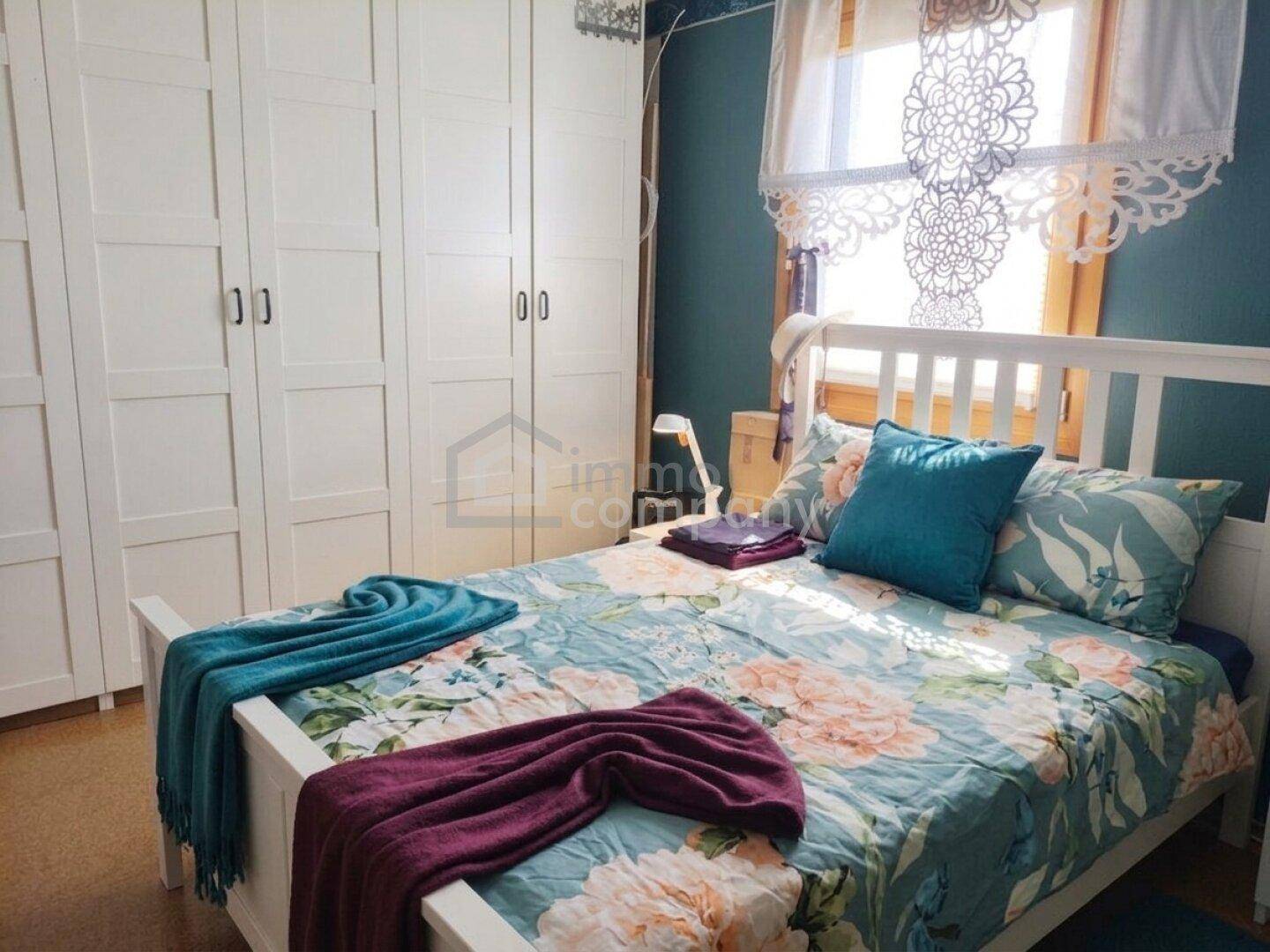 Gemütliches Schlafzimmer mit Doppelbett, Einbauschränken und farbiger Wandgestaltung.