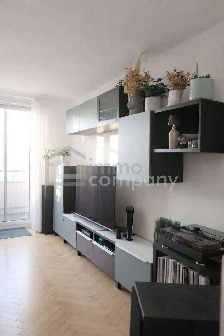 Modern eingerichtetes Wohnzimmer mit einer stilvollen Medienwand, Holzboden und Zugang zum Balkon.