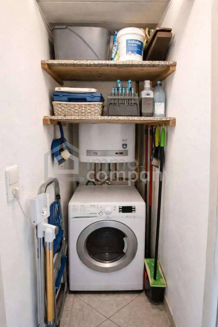 Praktischer Hauswirtschaftsraum mit Waschmaschine, Regalen und Reinigungsutensilien.