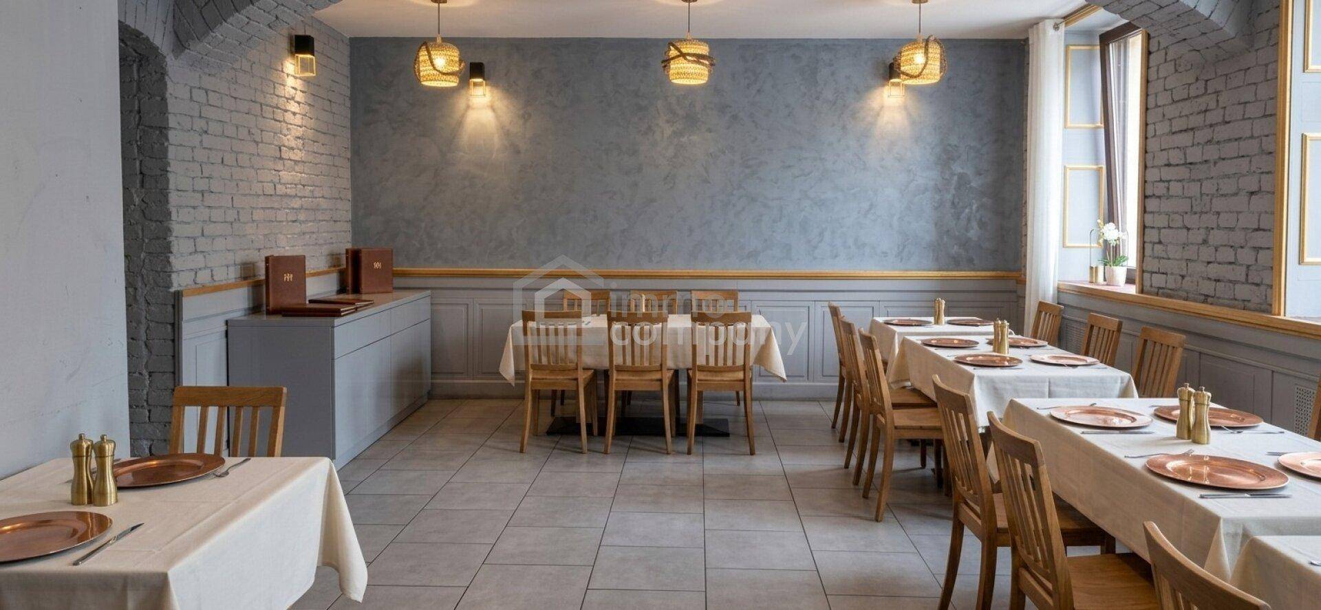 Gemütlicher Restaurantbereich mit grauen Ziegelwänden, Holztischen und einer warmen Beleuchtung, die eine angenehme Atmosphäre schafft.