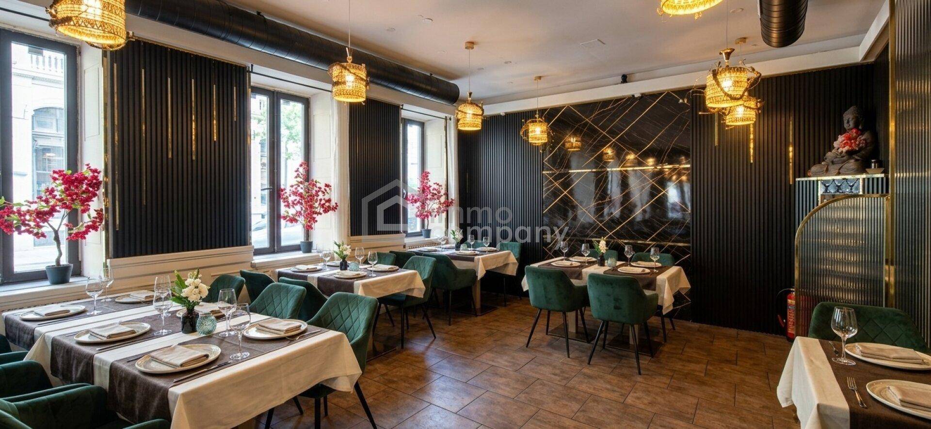 Stilvoller Restaurantraum mit gedeckten Tischen, großen Fenstern und modernen Dekorationselementen, die eine einladende Atmosphäre schaffen.
