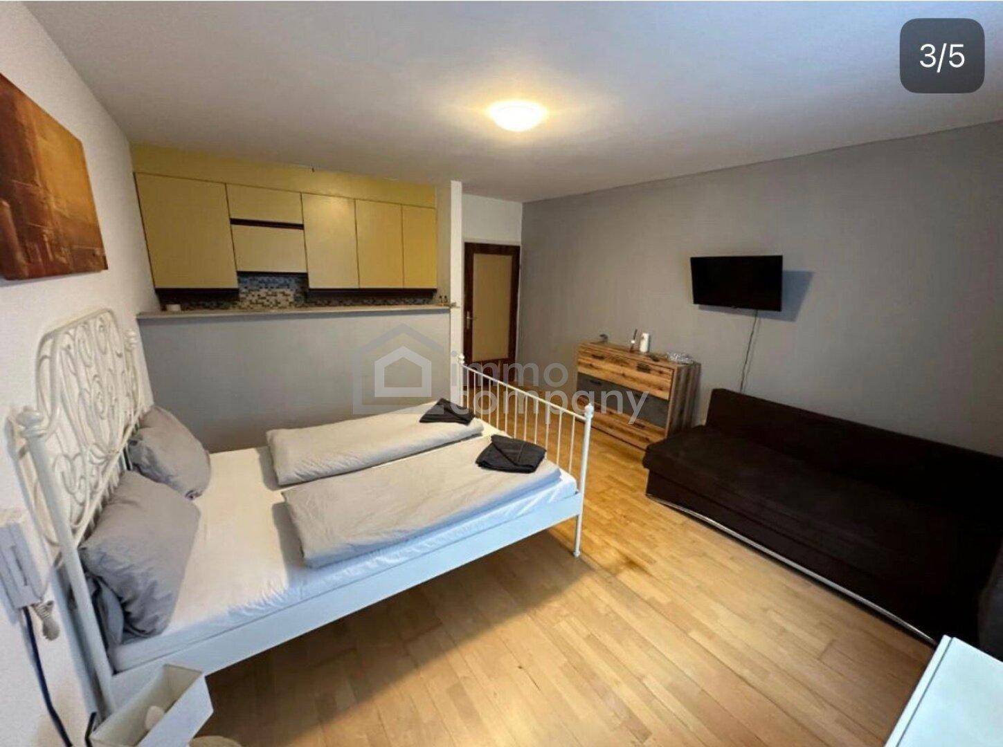 Kompaktes Studio-Apartment mit Bett, Sofa und integrierter Küchenzeile in modernem Design.