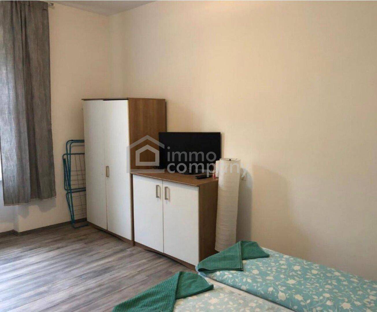 Schlafzimmer mit Kleiderschrank, TV-Möbel und Bett in funktionaler Einrichtung.