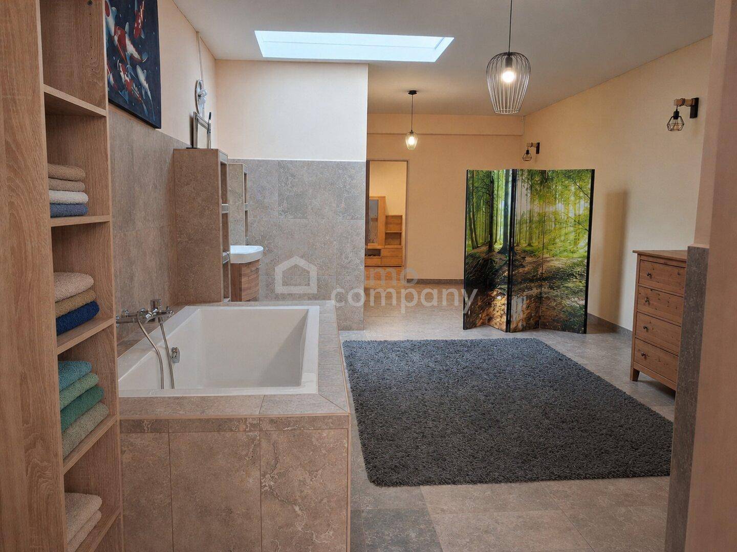Geräumiges Badezimmer mit Badewanne, Waschbecken und dekorativem Raumteiler.