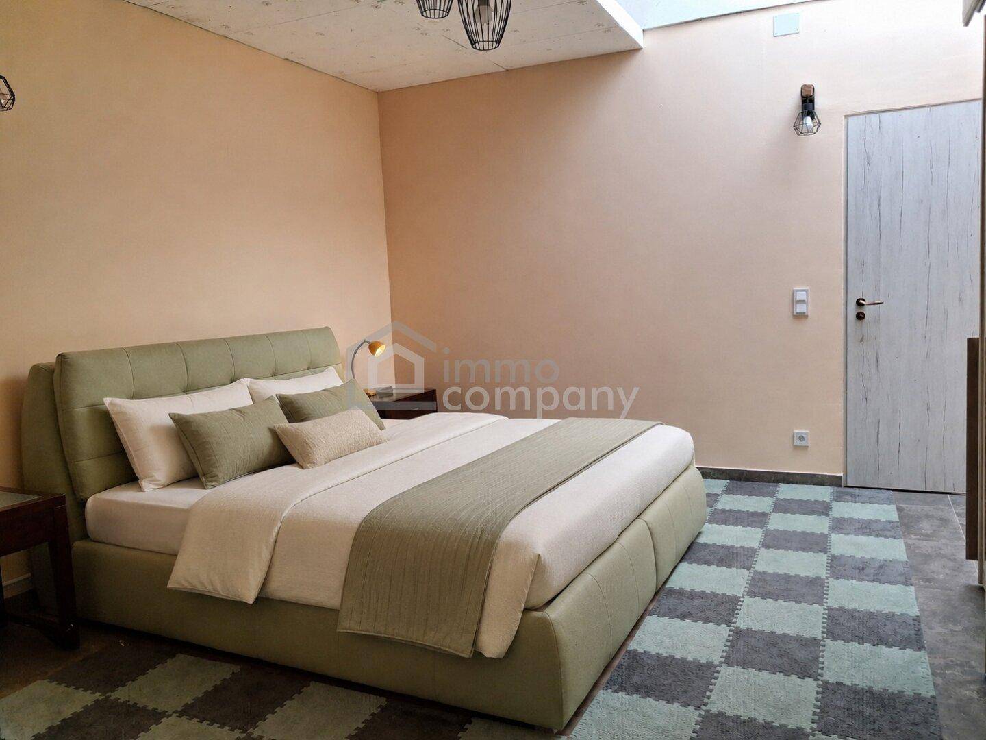 Helles Schlafzimmer mit modernem Bett, Teppichboden und Oberlicht für natürliches Licht.