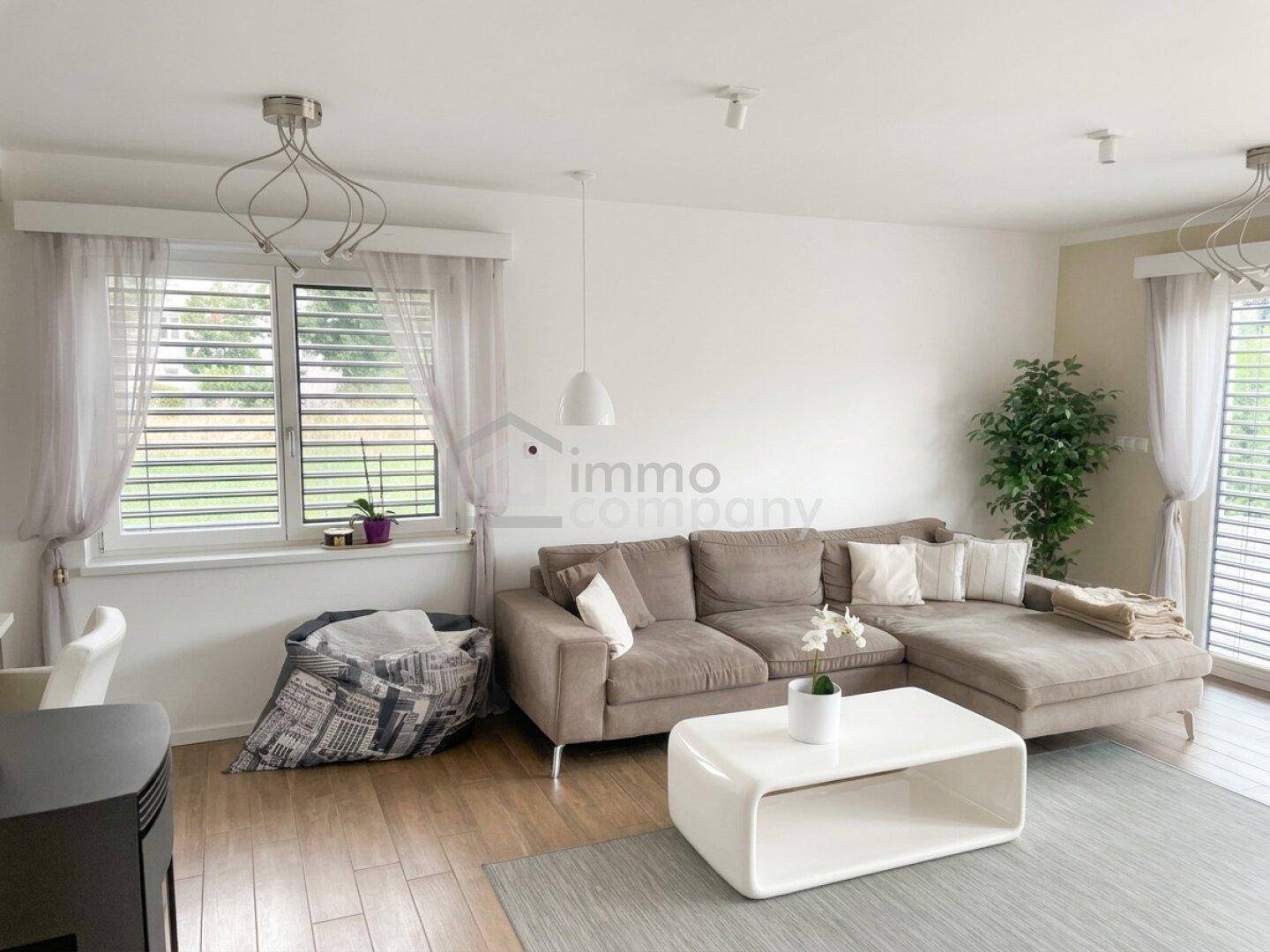 Helles Wohnzimmer mit beigem Ecksofa, modernem Couchtisch und Holzboden.