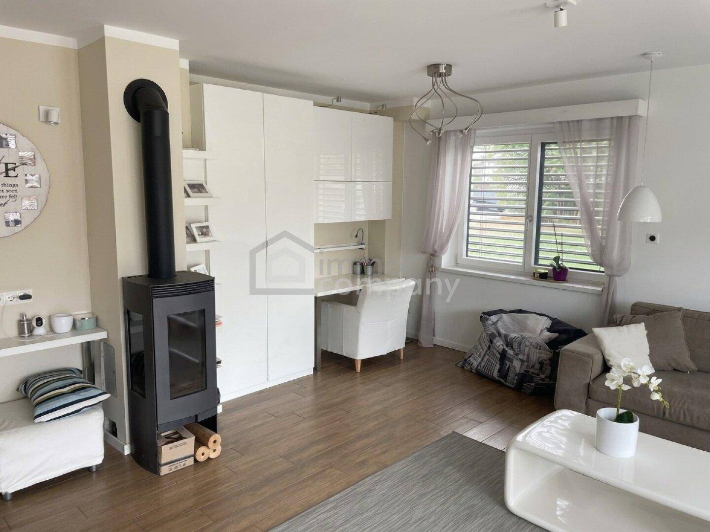 Gemütliches Wohnzimmer mit modernem Kaminofen, Holzboden und weißem Stauraum.