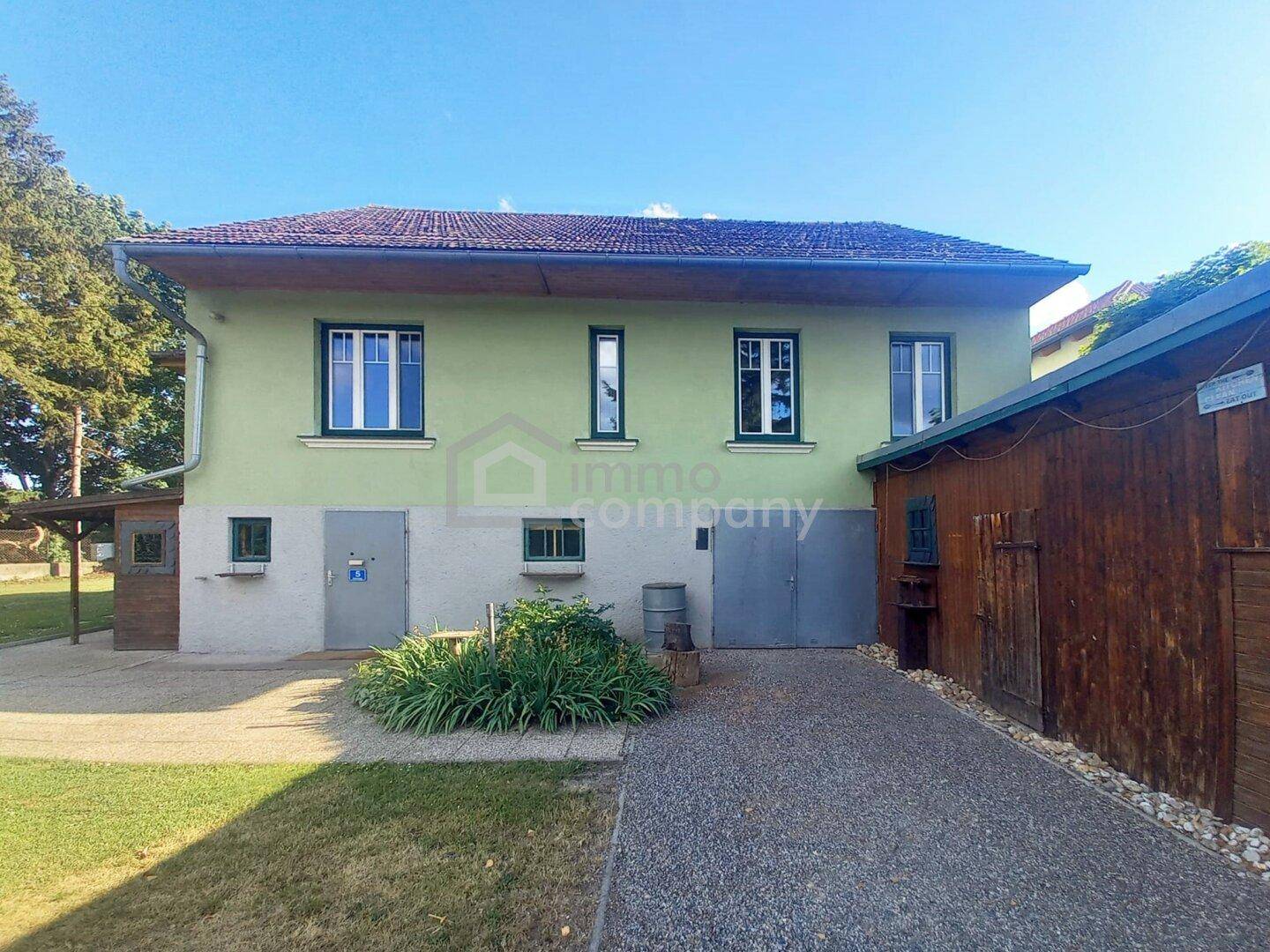 Rückansicht des Hauses mit mehreren Fenstern und zwei Zugängen im Erdgeschoss.