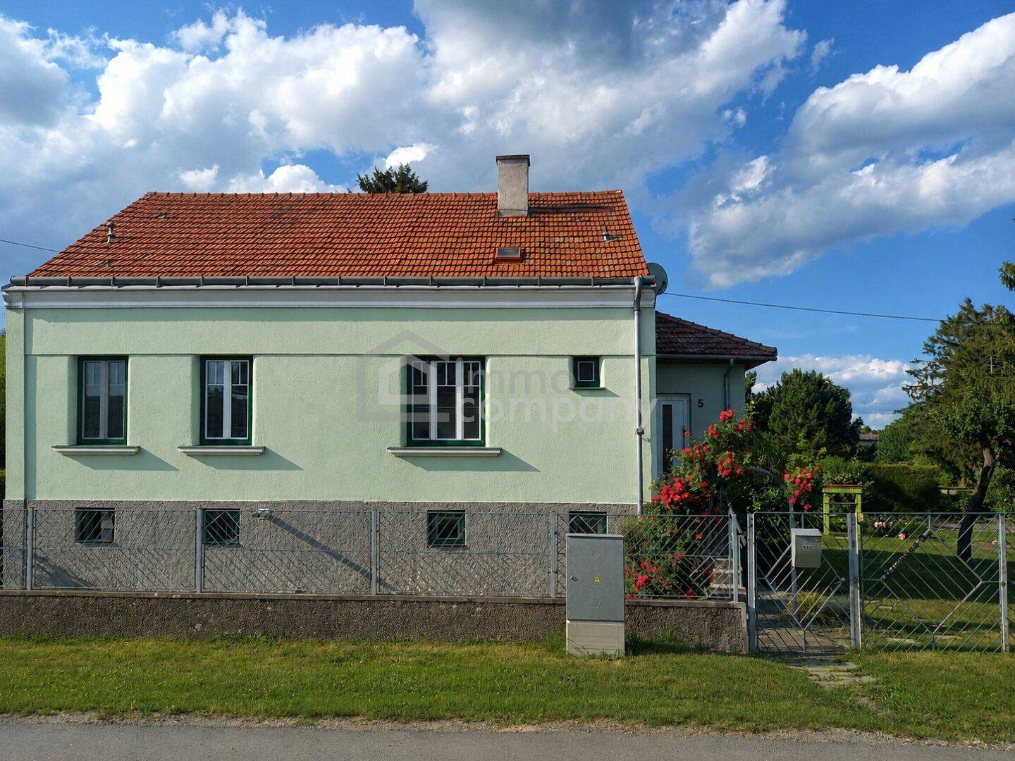 Seitenansicht des Hauses von der Straße mit rotem Ziegeldach und gepflegter Fassade.
