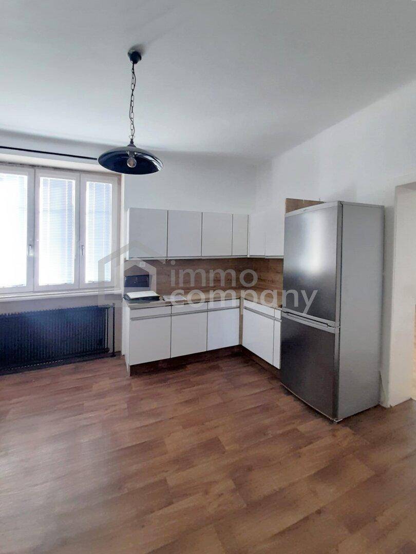Helle Küche mit weißen Schränken, Holz-Arbeitsplatten und einem großen Kühlschrank.