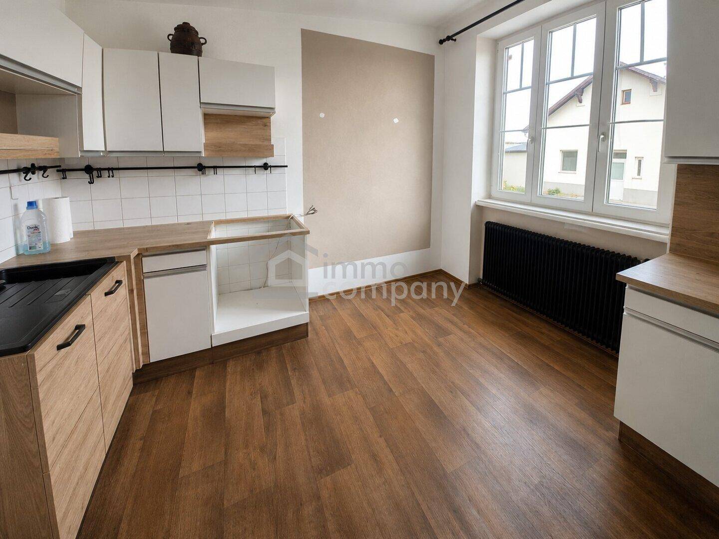 Geräumige Küche mit Holz-Arbeitsplatten, weißen Unterschränken und Platz für Geräte.