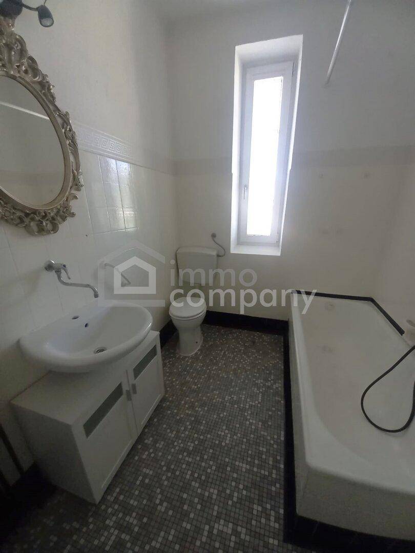 Badezimmer mit Badewanne, Waschbecken und WC, ausgestattet mit weißen Fliesen und Fenster.