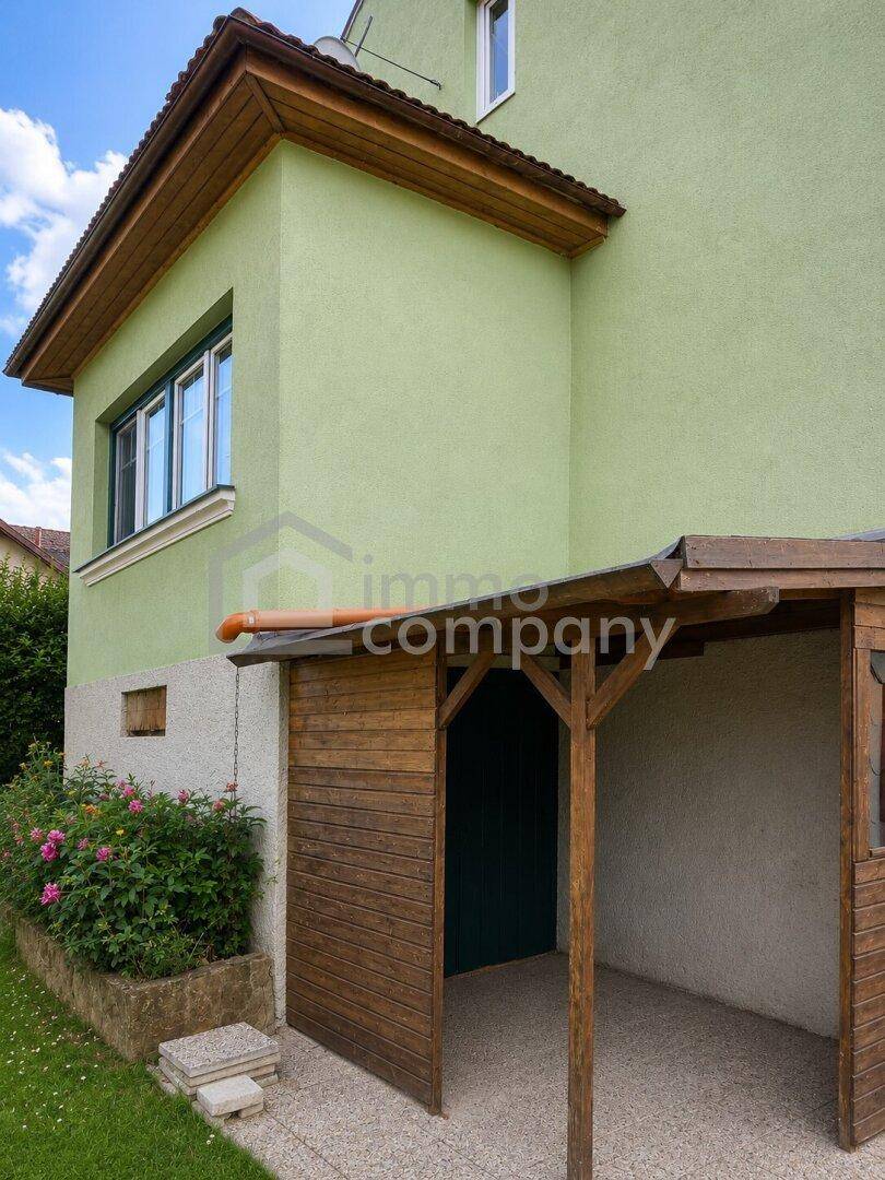 Seitenansicht des Hauses mit einem überdachten Eingangsbereich aus Holz.