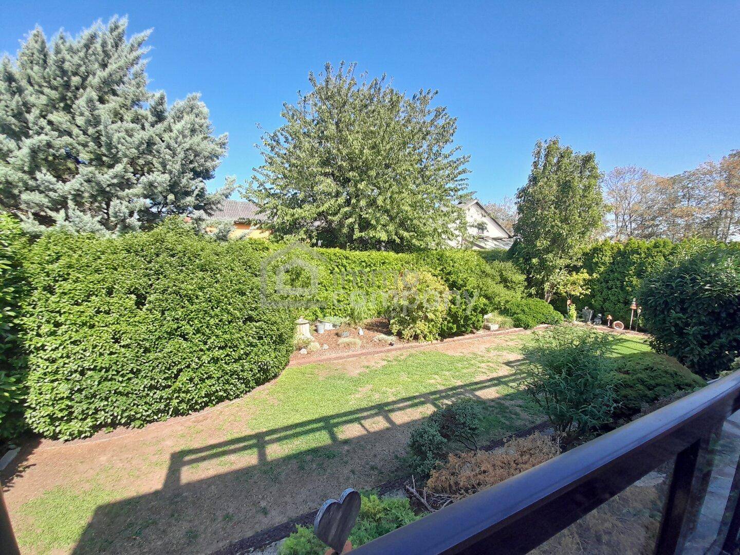 Gepflegter Gartenbereich mit Rasenfläche und hohen Hecken, von der Terrasse aus gesehen.