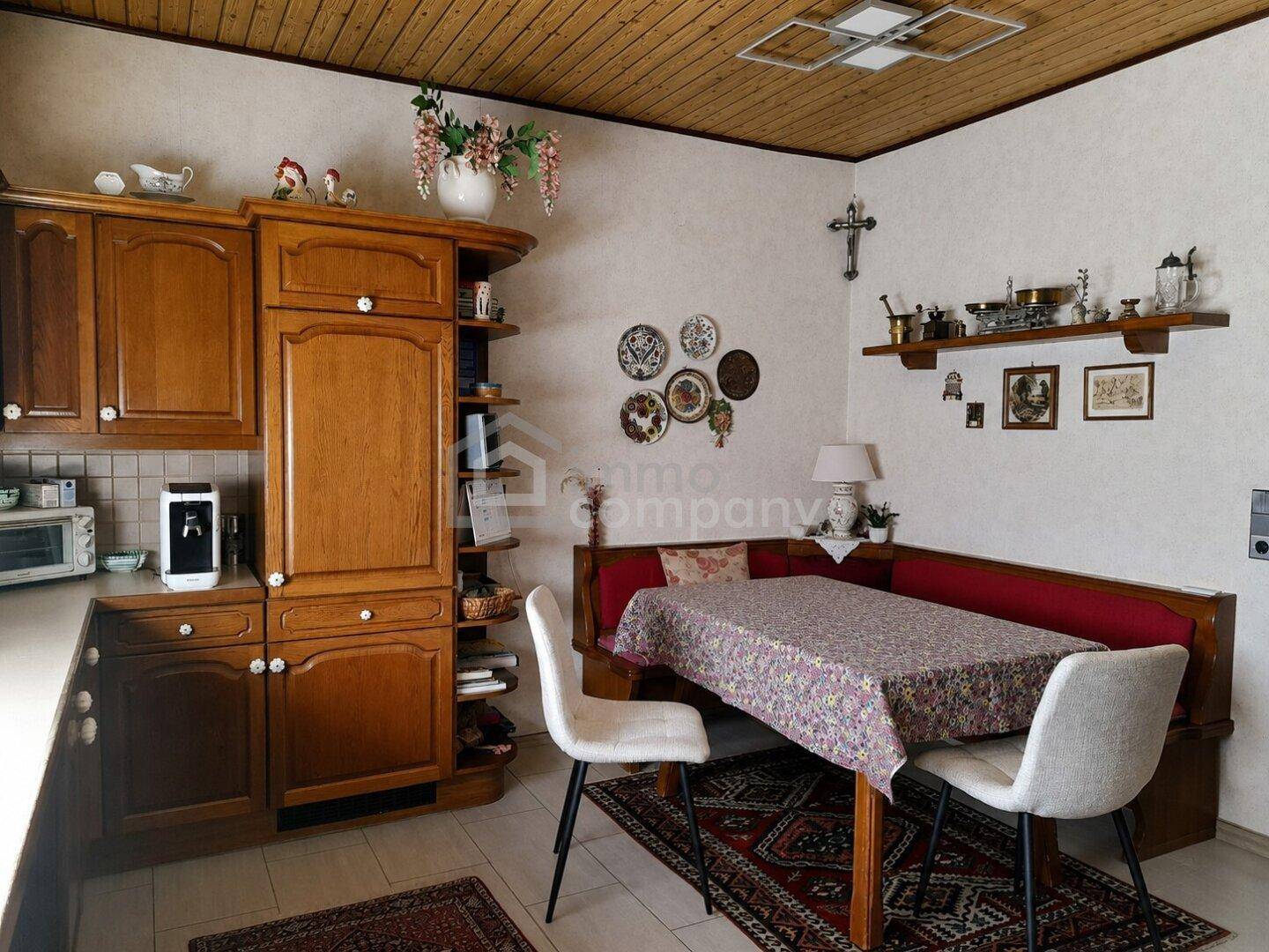 Wohnliche Küche mit Holzschränken, Essecke und Fliesenboden, ideal für Familienmahlzeiten.