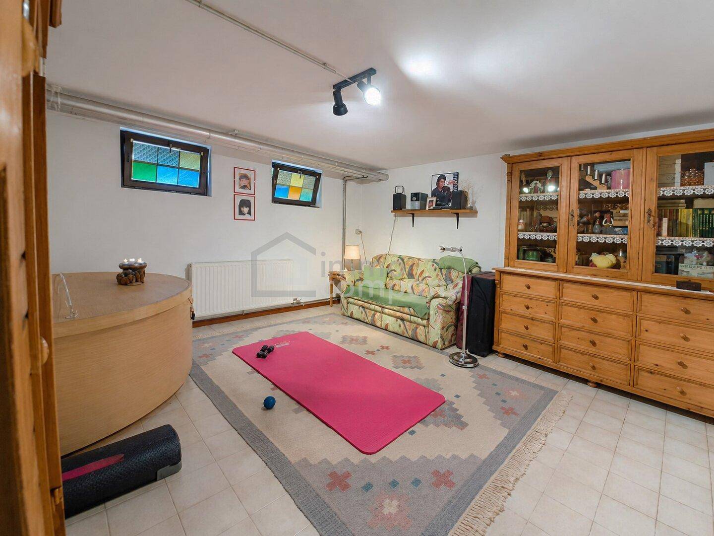 Gemütlicher Kellerraum mit Fliesenboden und Sofa, ideal als Hobby- oder Freizeitbereich.