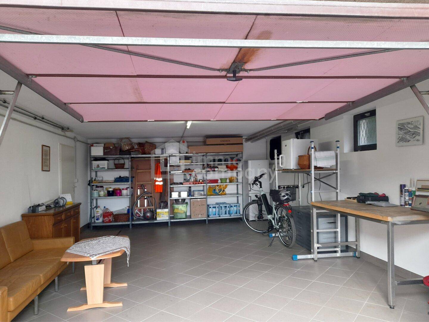 Geräumige Garage mit viel Stauraum, Regalen und Werkbank, ideal für Fahrzeuge und Hobbys.