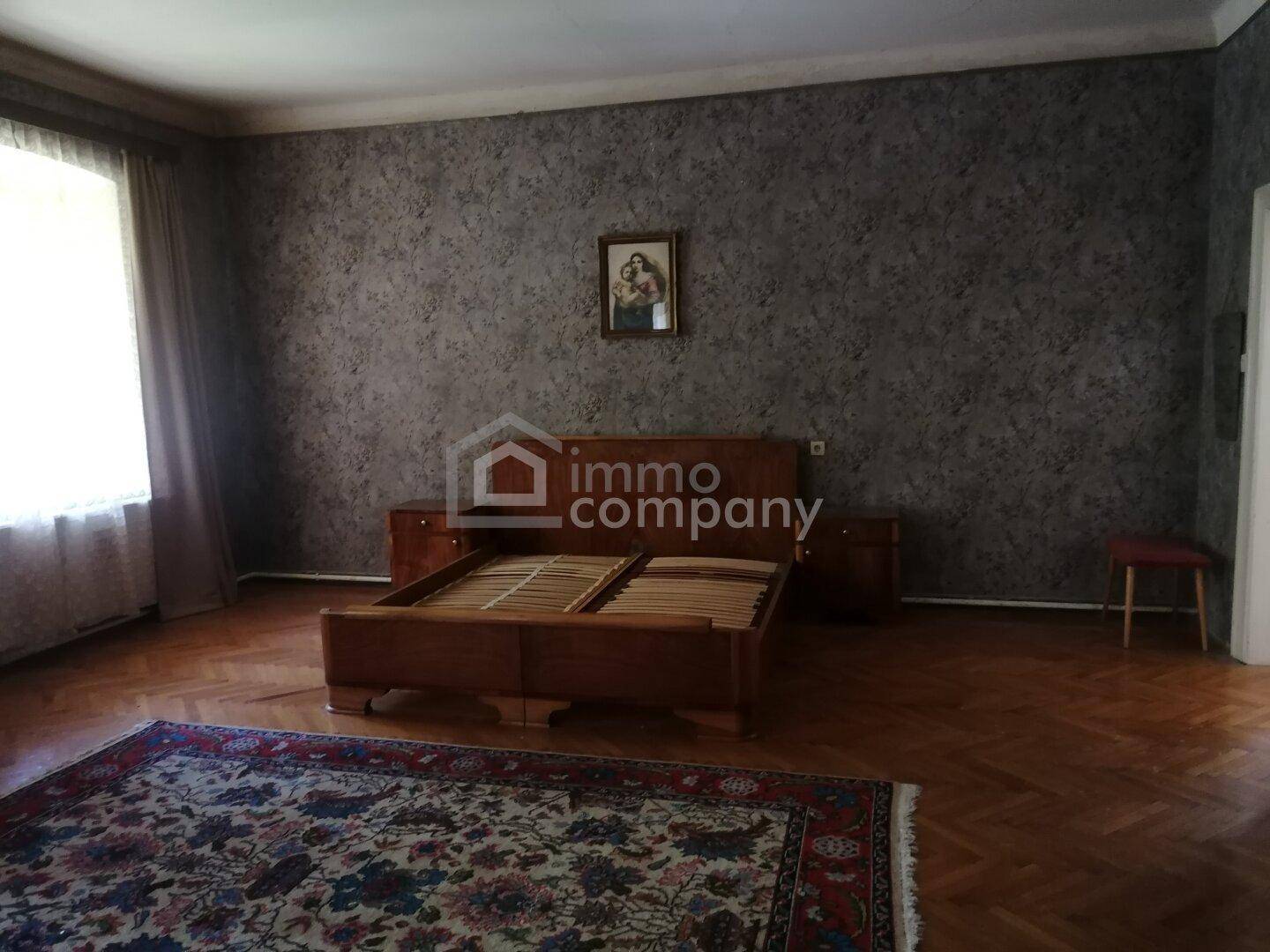 Schlafzimmer mit dunkler Tapete, Holzbett und Parkettboden, bietet viel Raum.