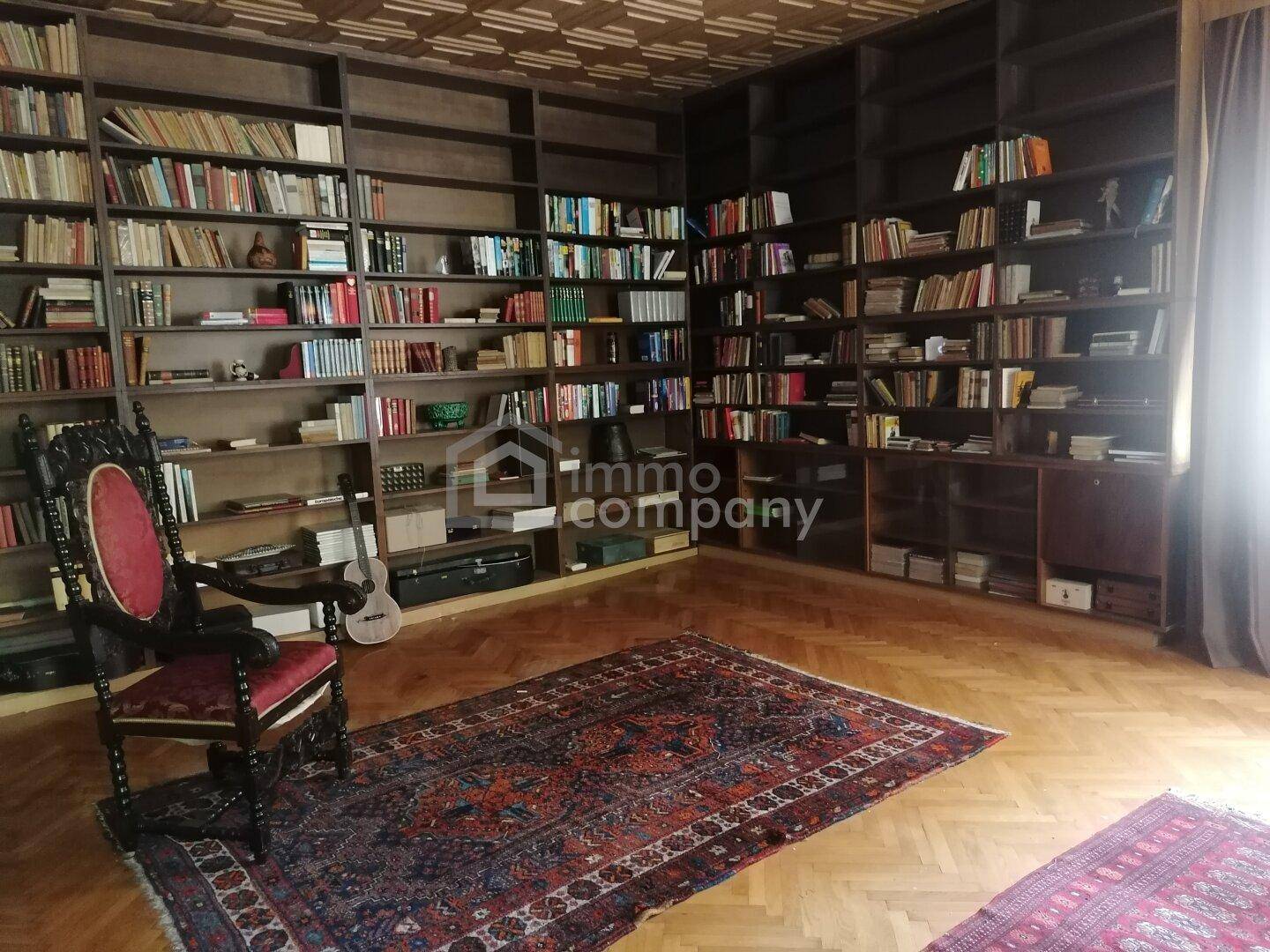 Großzügige Bibliothek mit raumhohen Bücherregalen und klassischem Parkettboden.