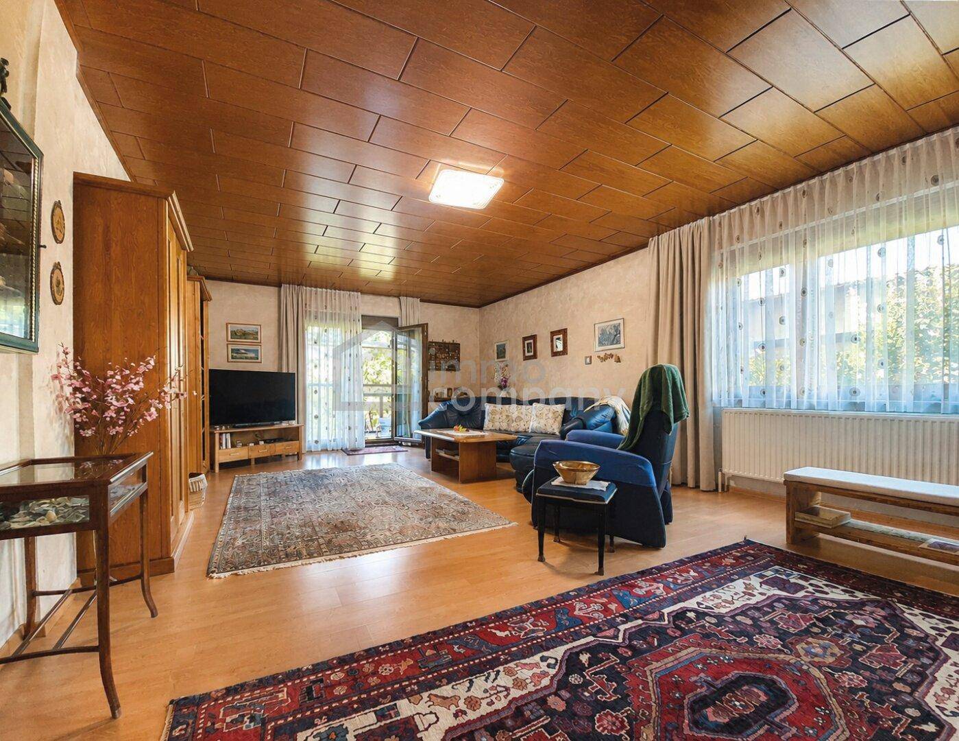 Gemütliches Wohnzimmer mit Holzdeckenverkleidung, Parkettboden und großem Fenster.