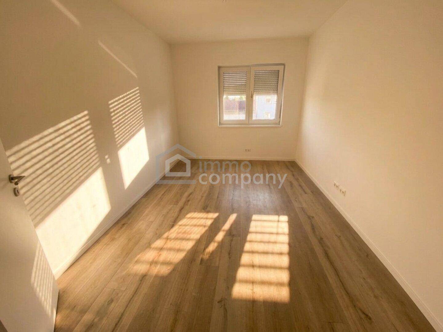 Ruhiges Schlafzimmer mit Holzboden und Fenster mit Rollladen, ideal für Erholung.
