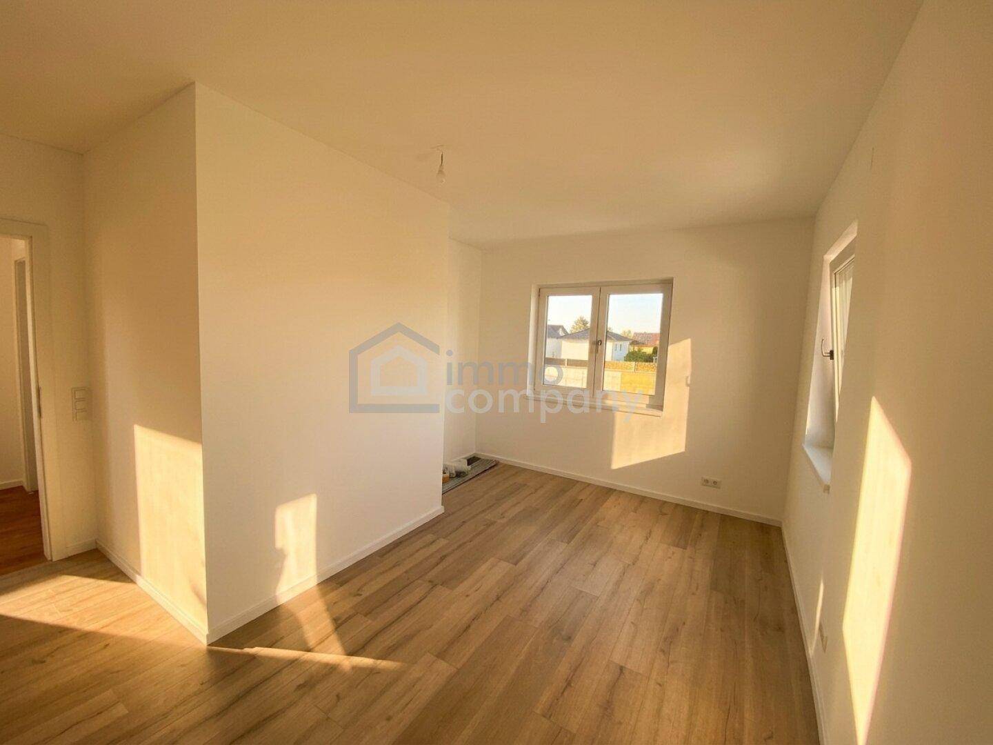 Helles Zimmer mit Holzboden und zwei Fenstern, bietet vielseitige Nutzungsmöglichkeiten.