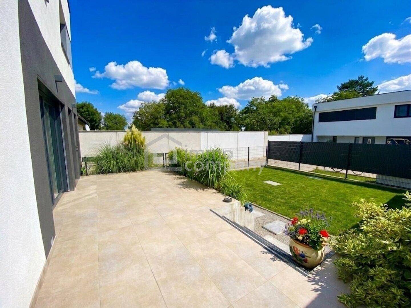 Geräumige, geflieste Terrasse mit Pflanzen und Blick auf den Garten.