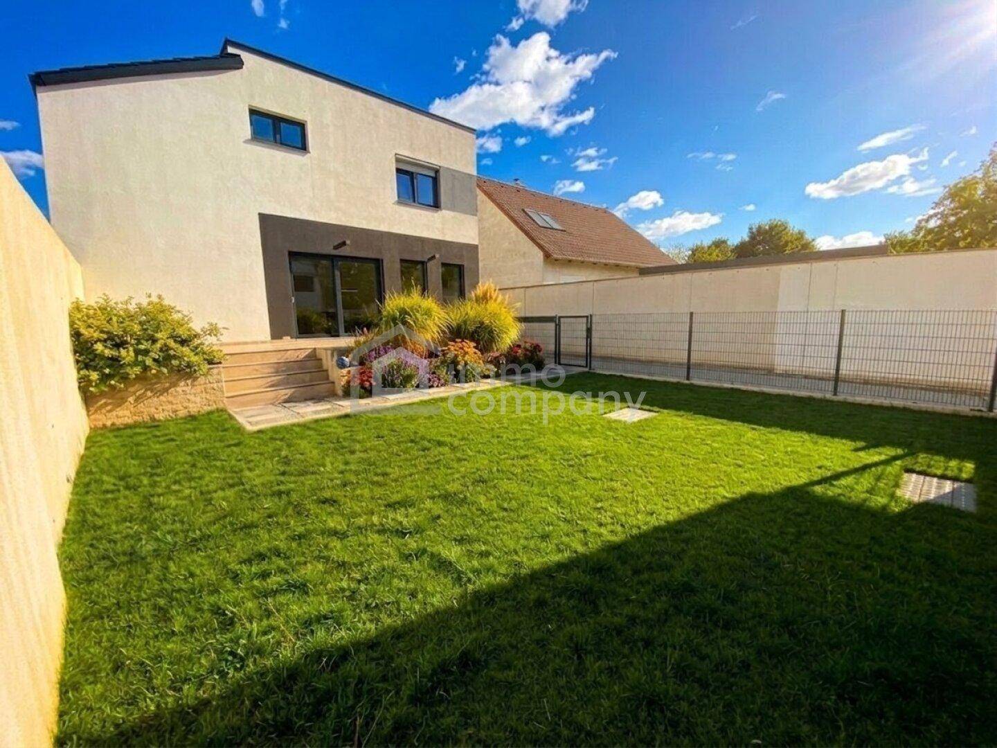 Gepflegter Garten mit Rasenfläche und kleiner Holzterrasse hinter dem Haus.
