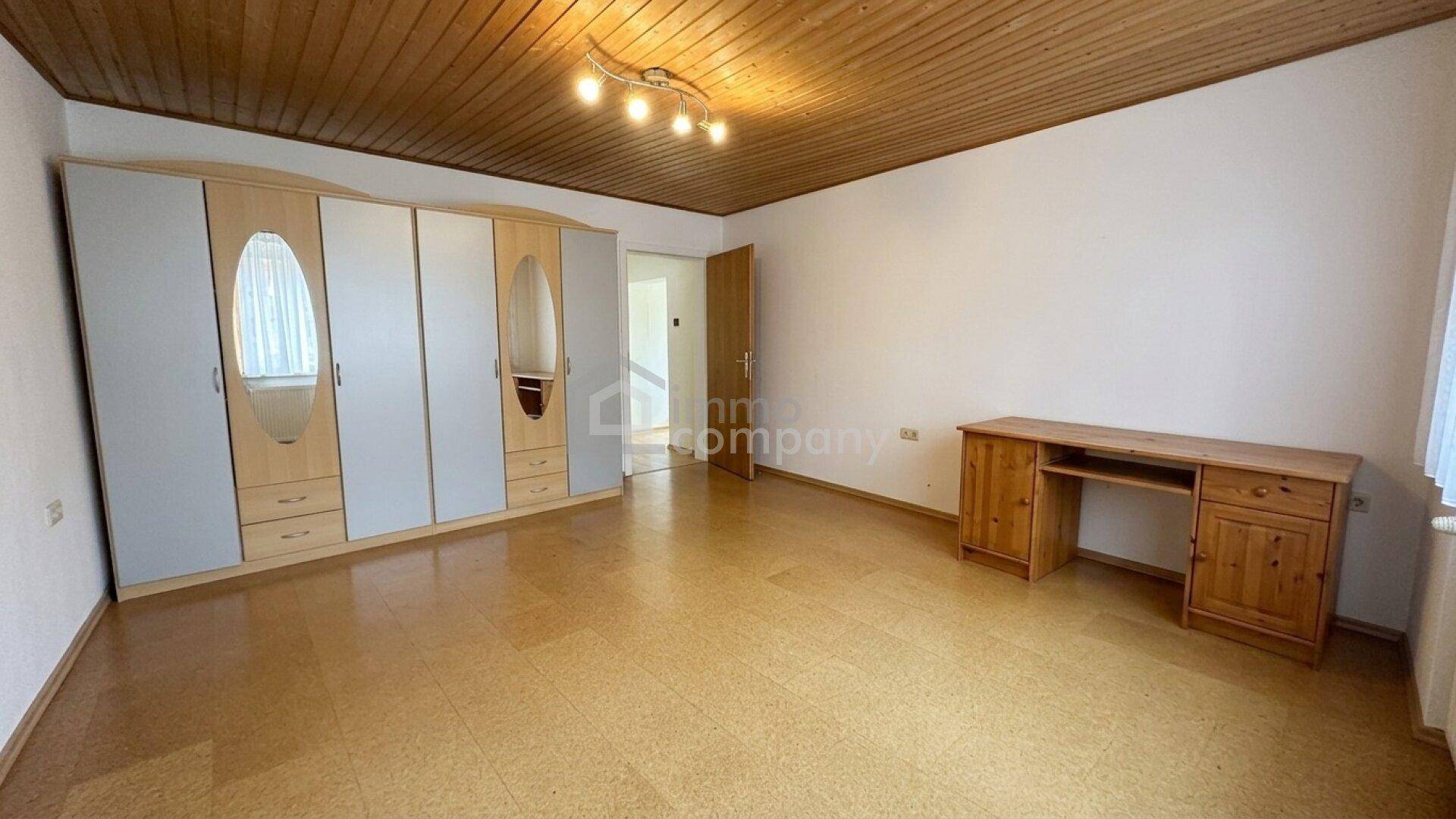 Geräumiges Schlafzimmer mit großem Kleiderschrank, Schreibtisch und Korkboden, mit Holzdecke.