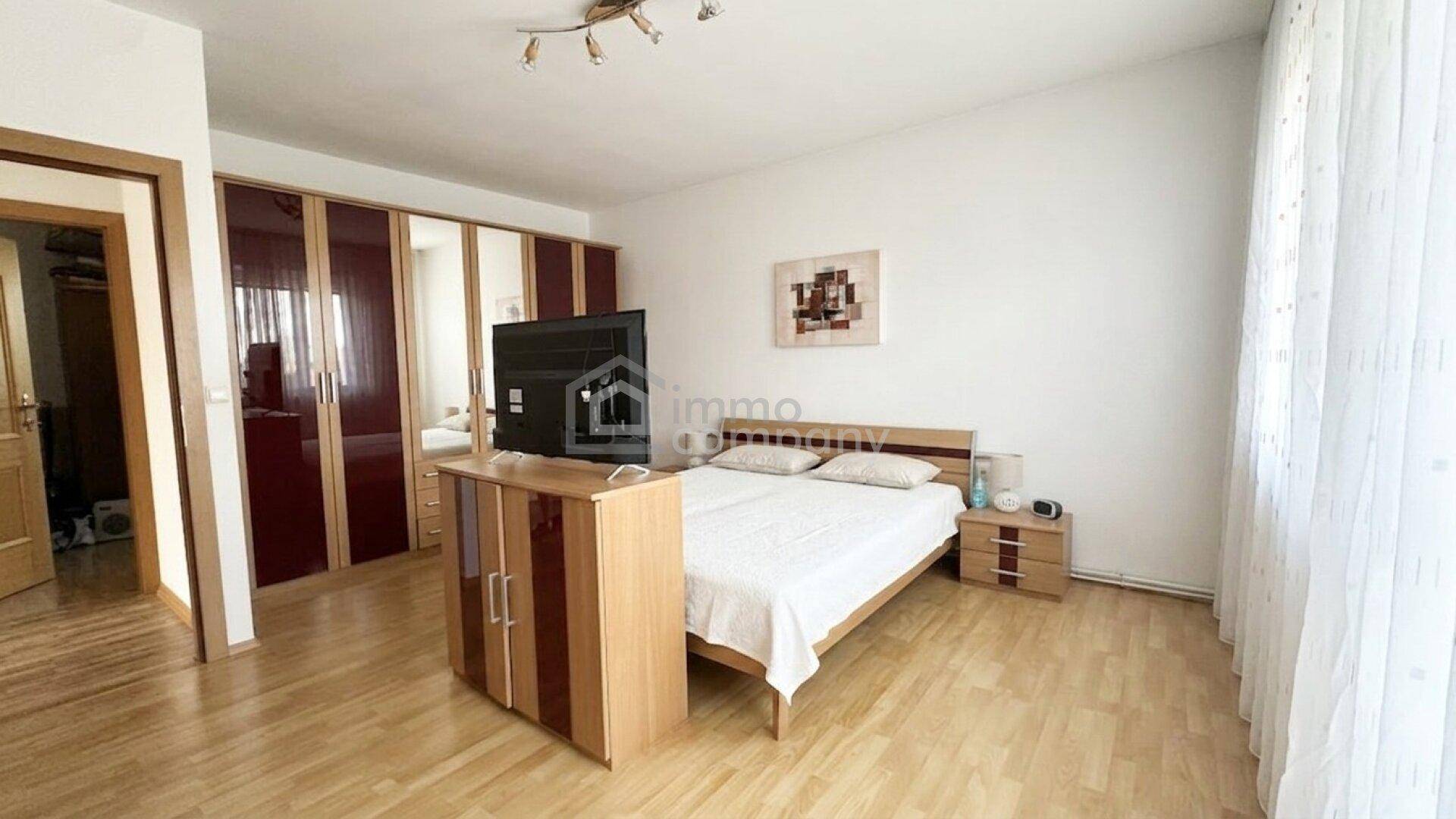 Schlafzimmer mit Doppelbett, Nachttischen und großem Kleiderschrank mit Spiegeltüren, hell und geräumig.