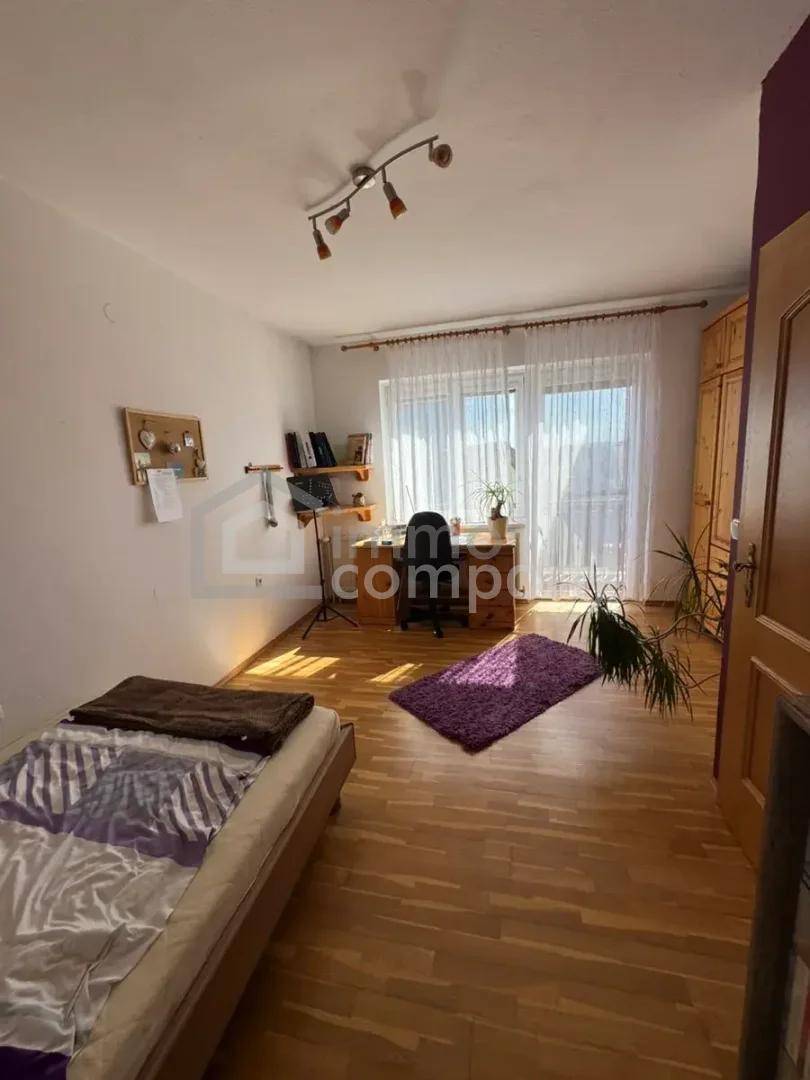 Helles Schlafzimmer mit Laminatboden, großem Fenster und integriertem Arbeitsbereich.