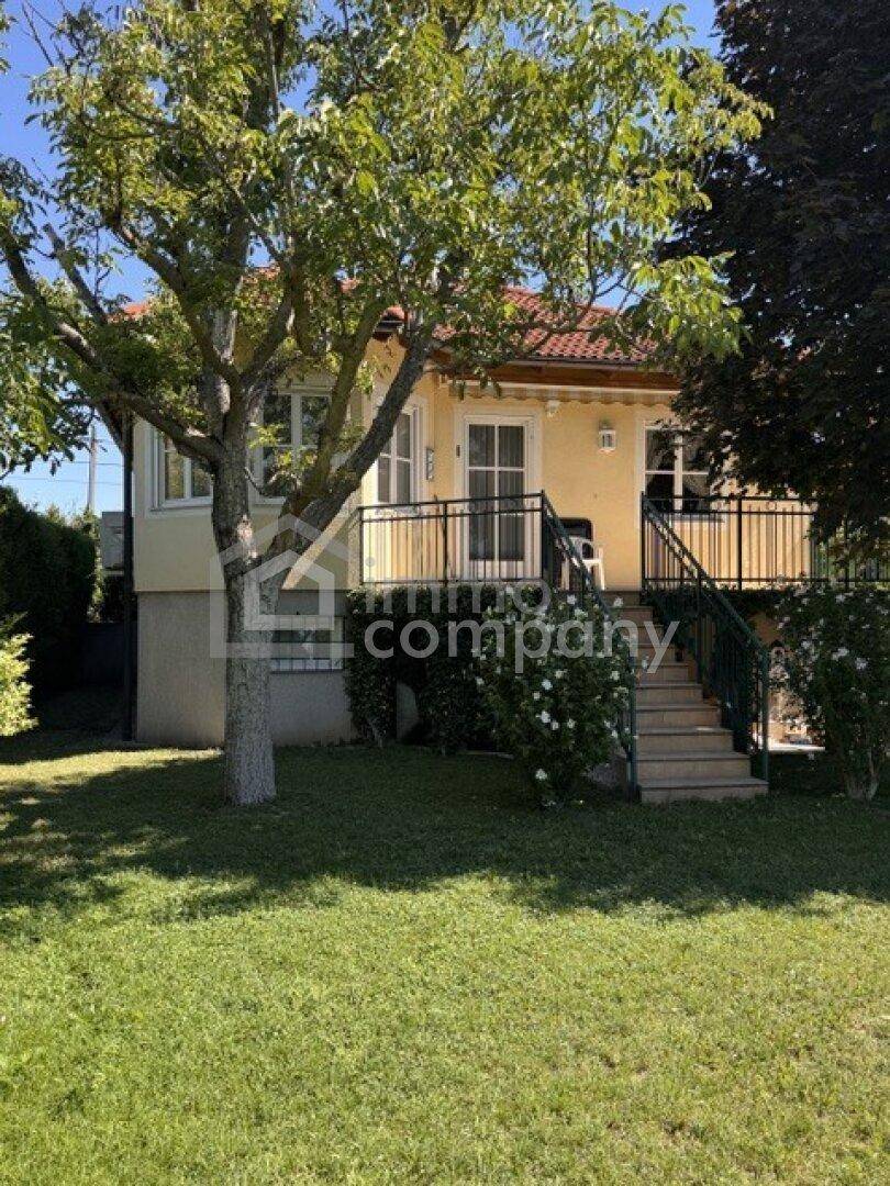 Gelbes Haus mit rotem Ziegeldach, umgeben von einem gepflegten Garten und Bäumen.