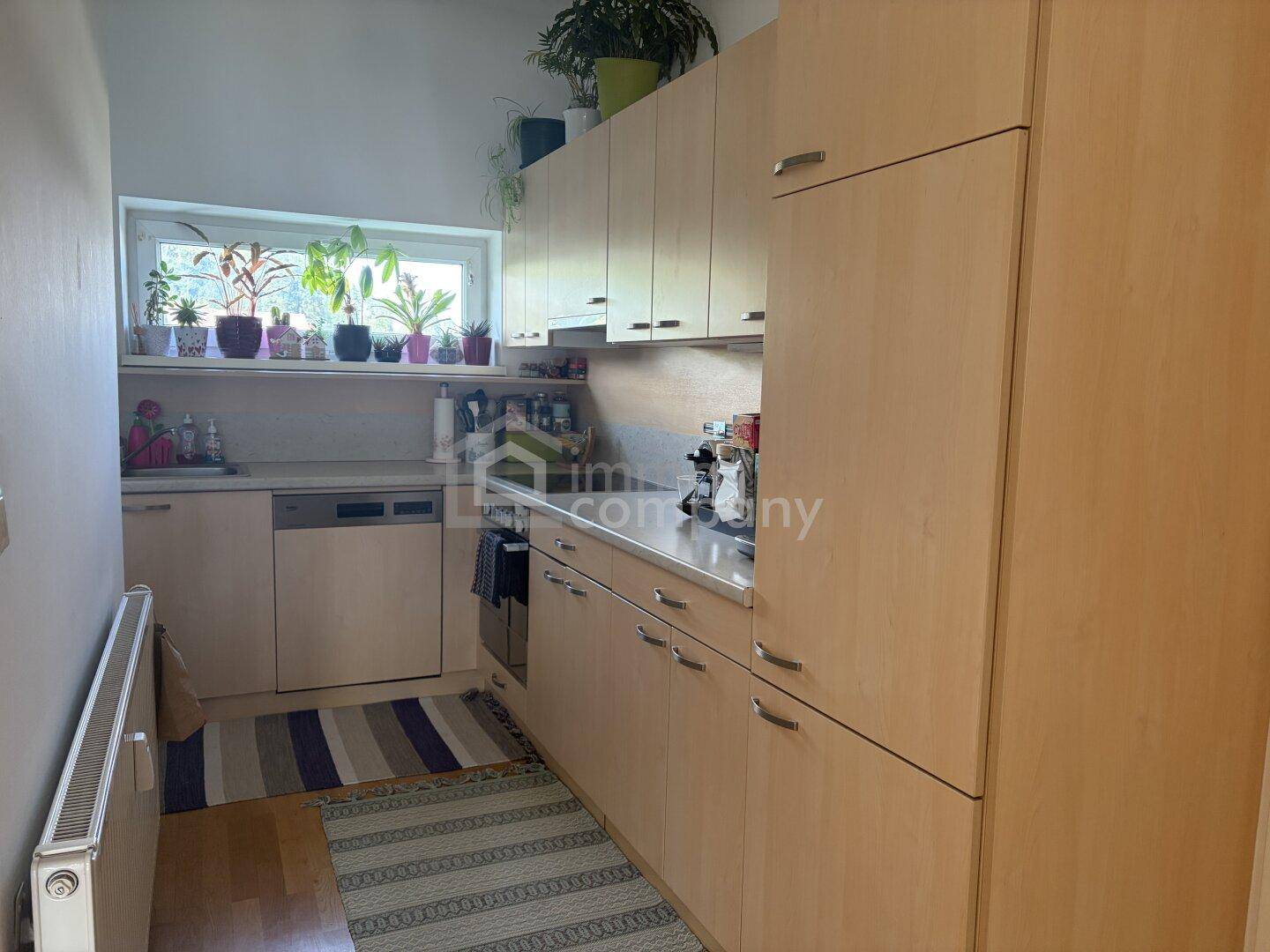 Funktionale Küche mit hellen Holzschränken, Fenster und integriertem Geschirrspüler.