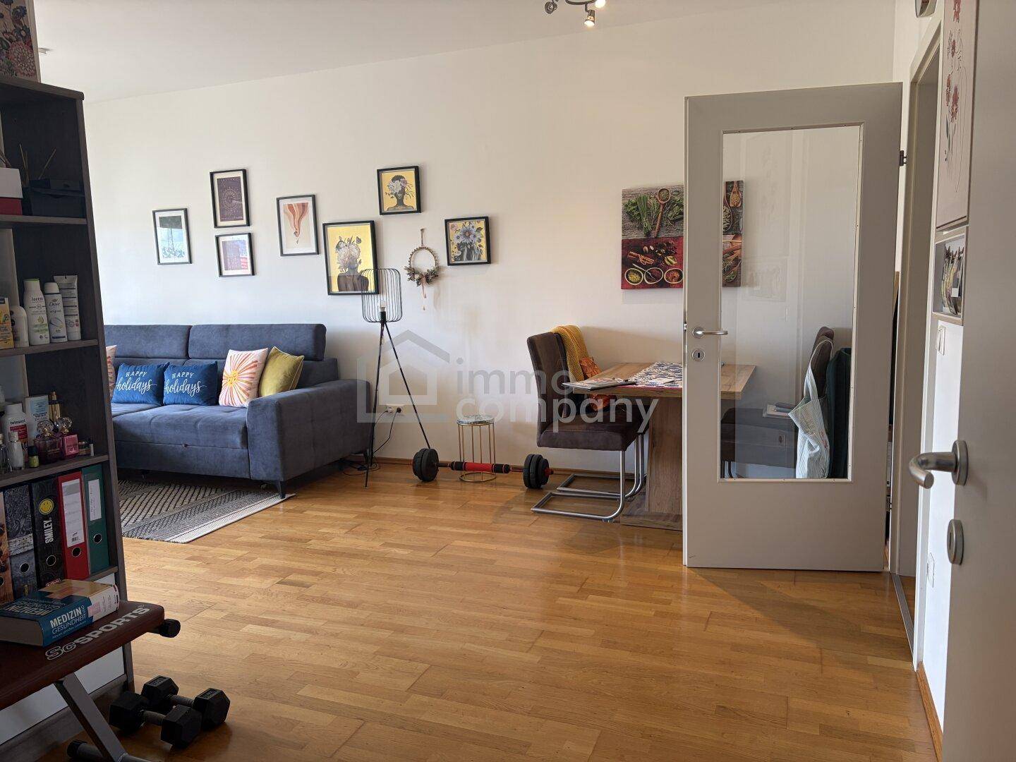 Helles Wohnzimmer mit Holzboden, einem Sofa und einem kleinen Essbereich.