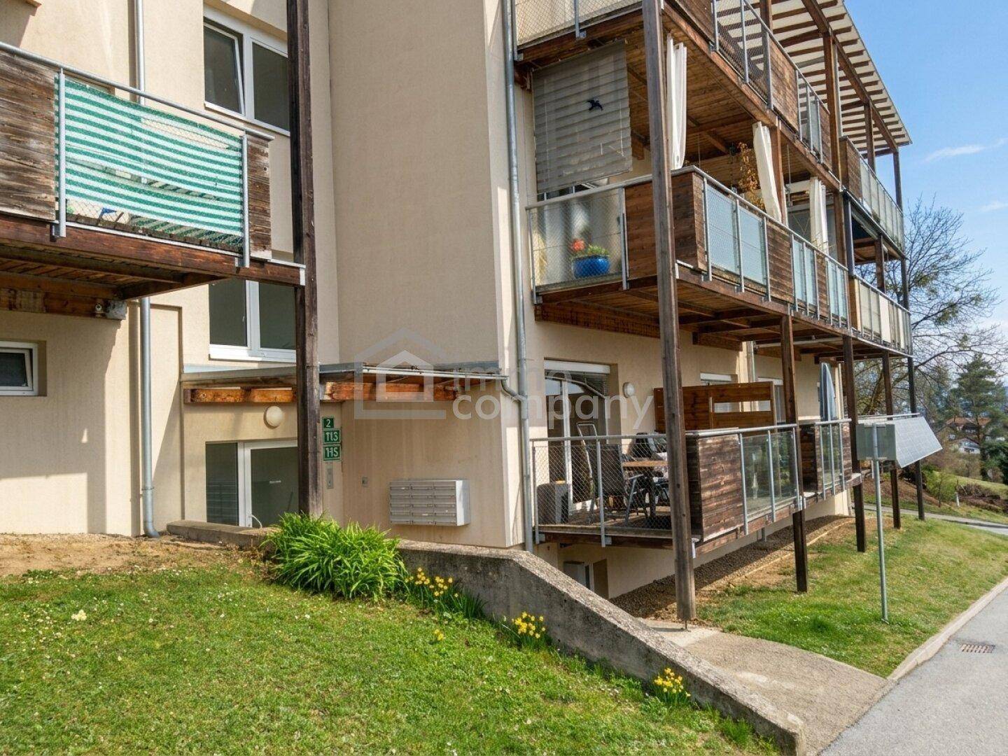 Mehrere Balkone mit Holzverkleidung und Glasgeländern an der Fassade eines modernen Gebäudes.