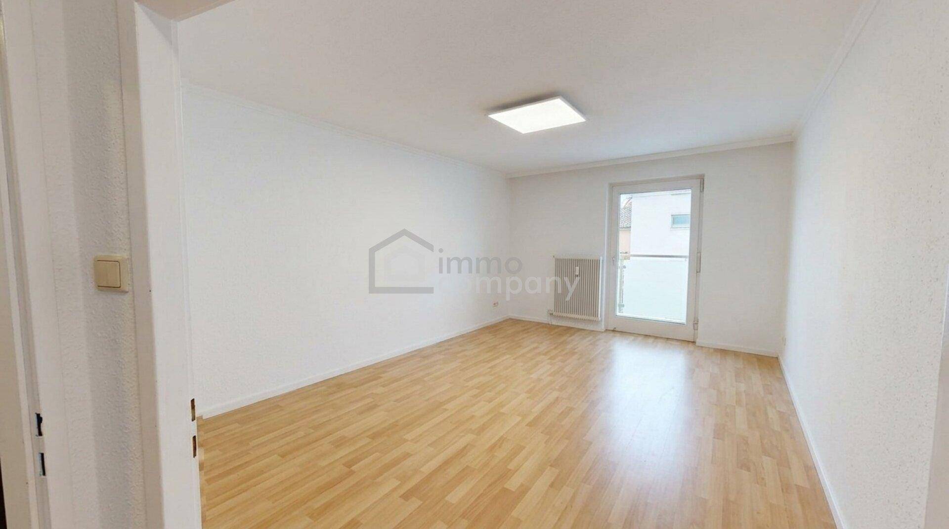 Helles Schlafzimmer mit Parkettboden und Zugang zu einem Balkon oder einer Terrasse.