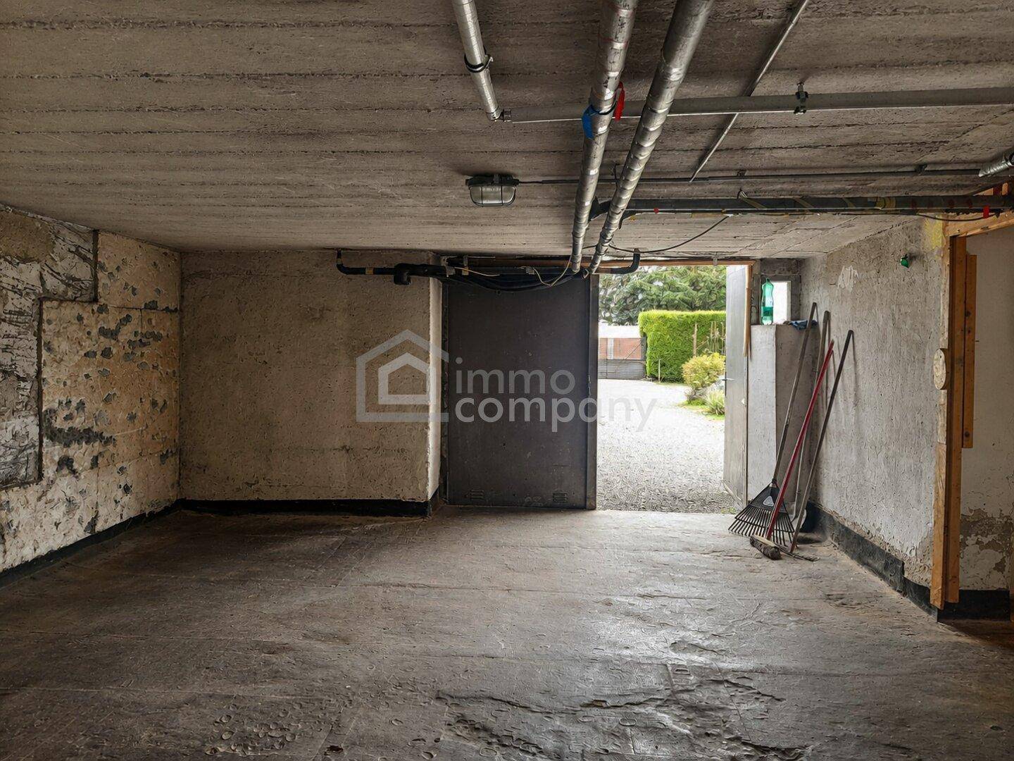 Geräumige Garage oder Kellerraum mit Betonboden und sichtbaren Rohrleitungen.