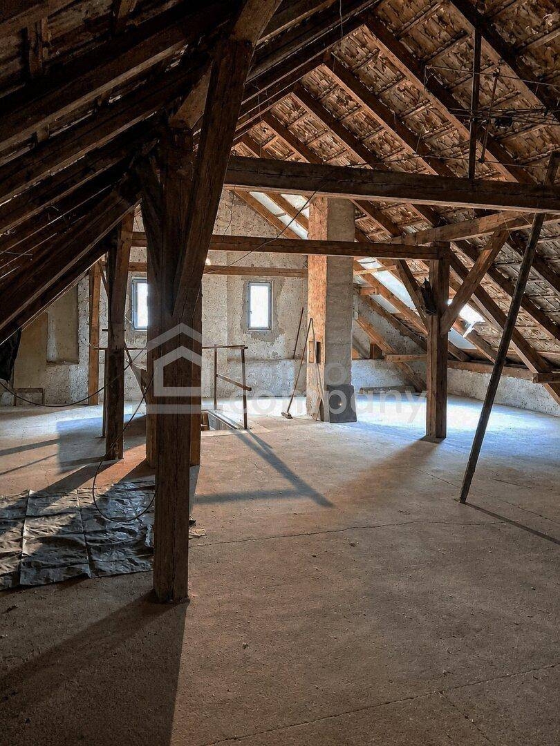 Großer, unfertiger Dachboden mit sichtbaren Holzbalken und Betonboden.