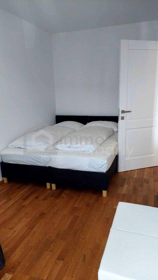 Schlafzimmer mit Doppelbett, Holzboden und weiß gestrichenen Wänden.